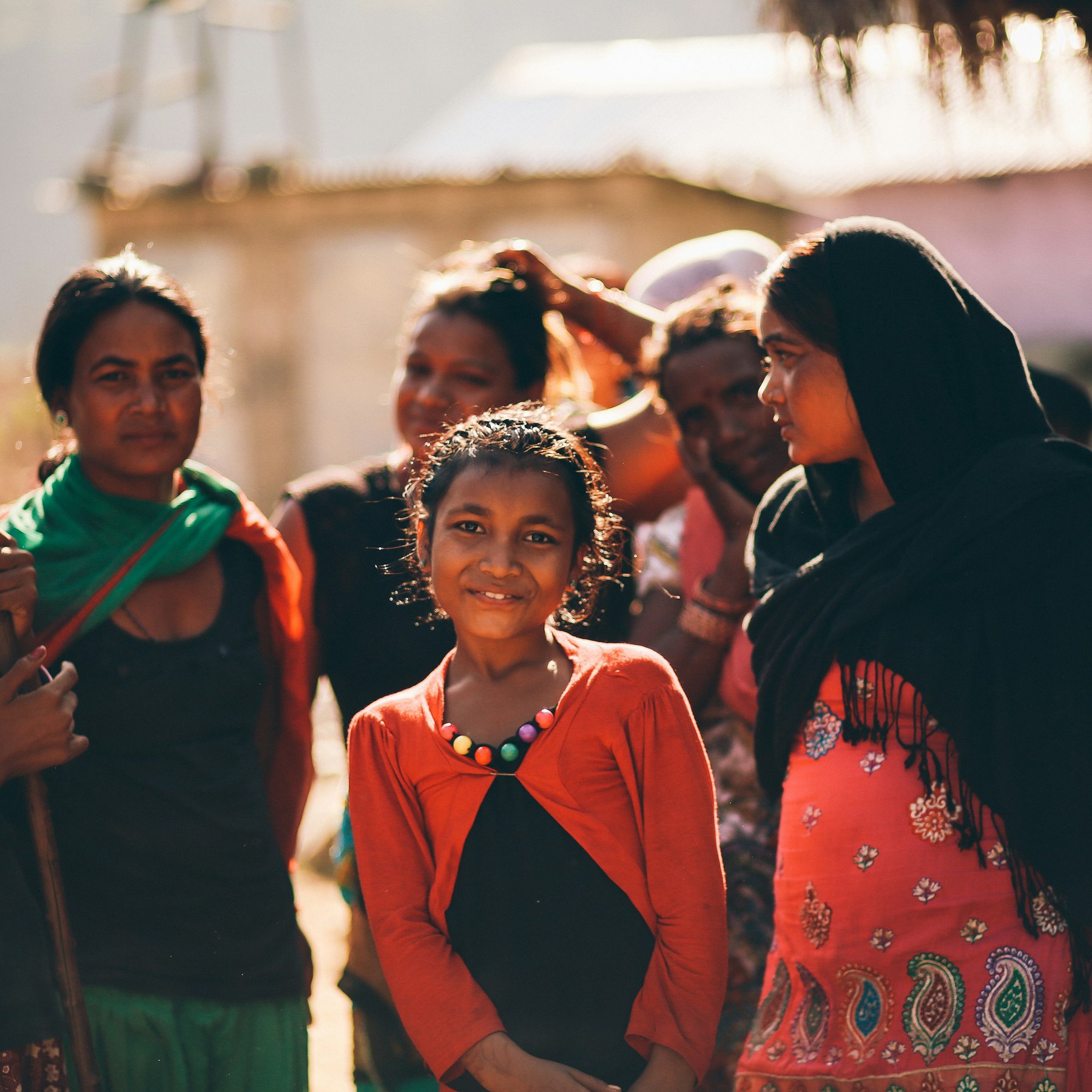 A girl stands among a group of women.