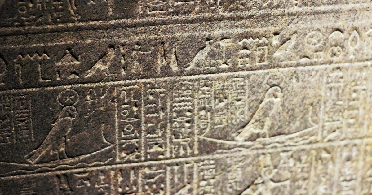 Ancient Egyptian figures and hieroglyphs carved into stone.
