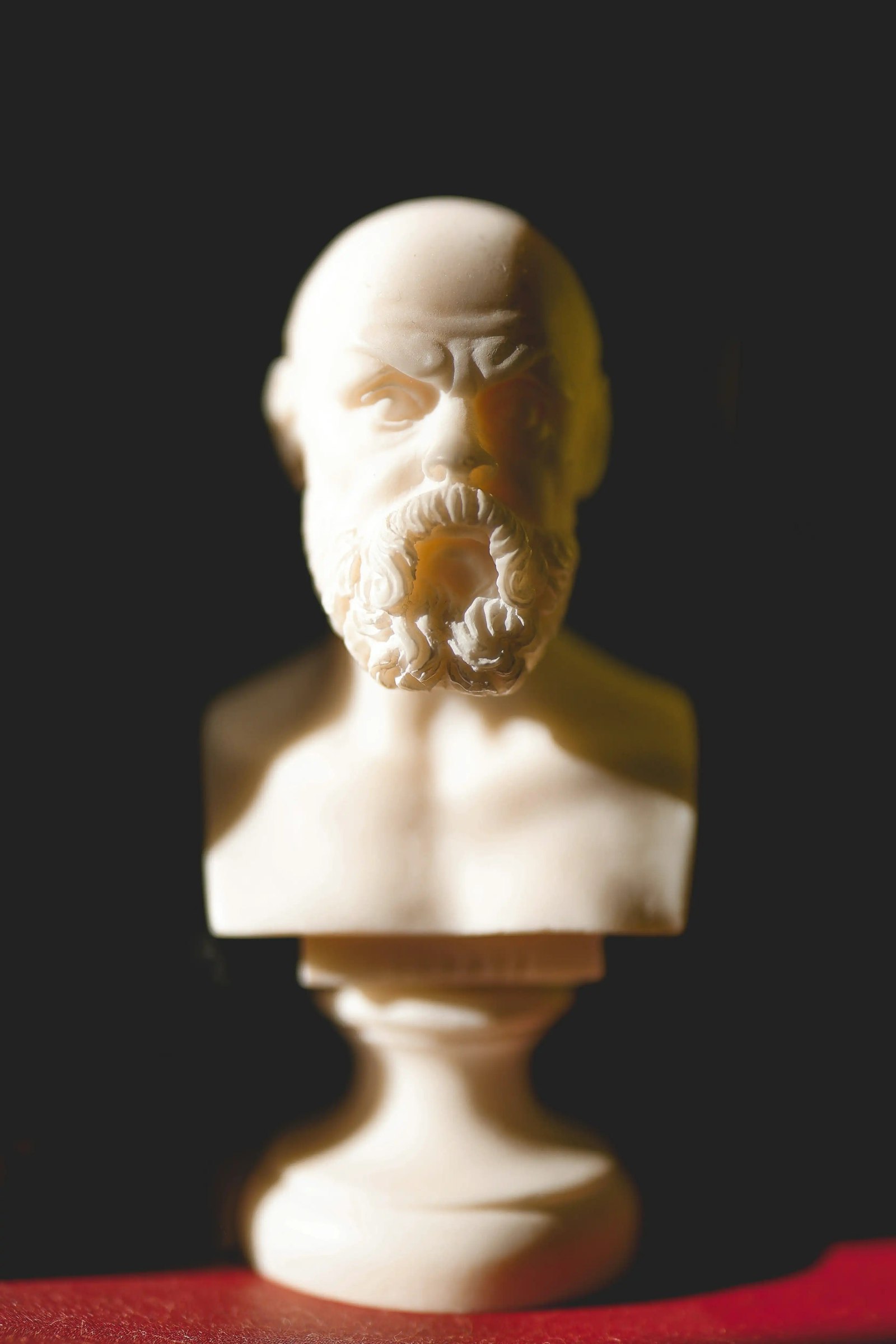A white bust of Socrates illuminated against a dark background.